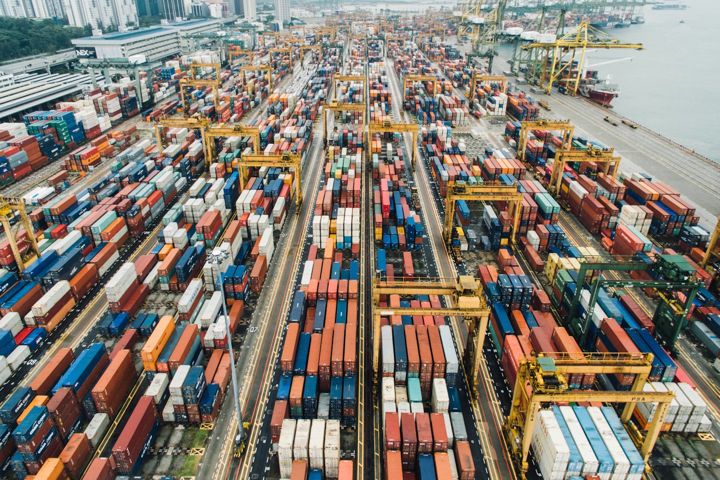 Aerial view of a busy cargo container port with gantry cranes and ships.