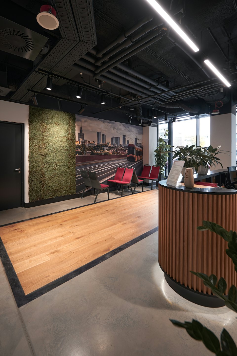 Modern office reception area with wooden desk and cityscape mural.