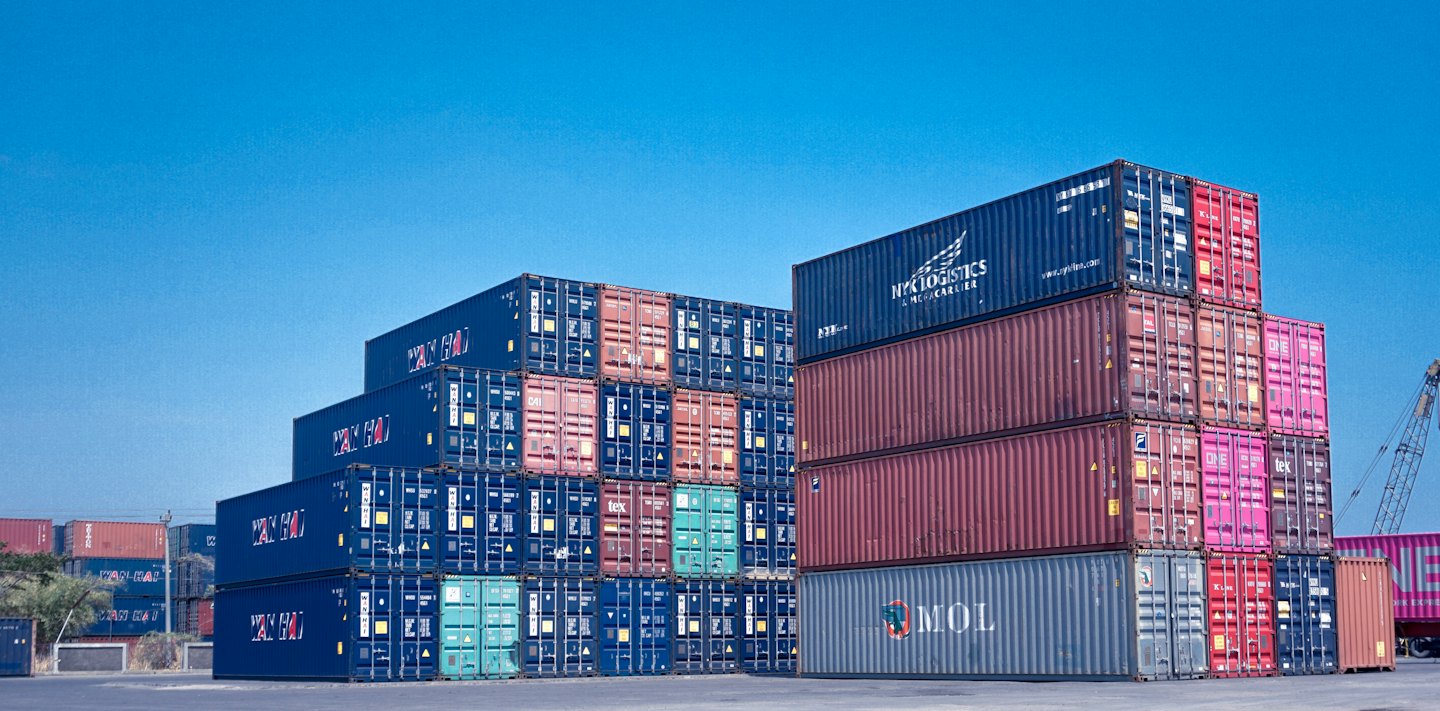 Brightly colored shipping containers stacked high at a busy port.
